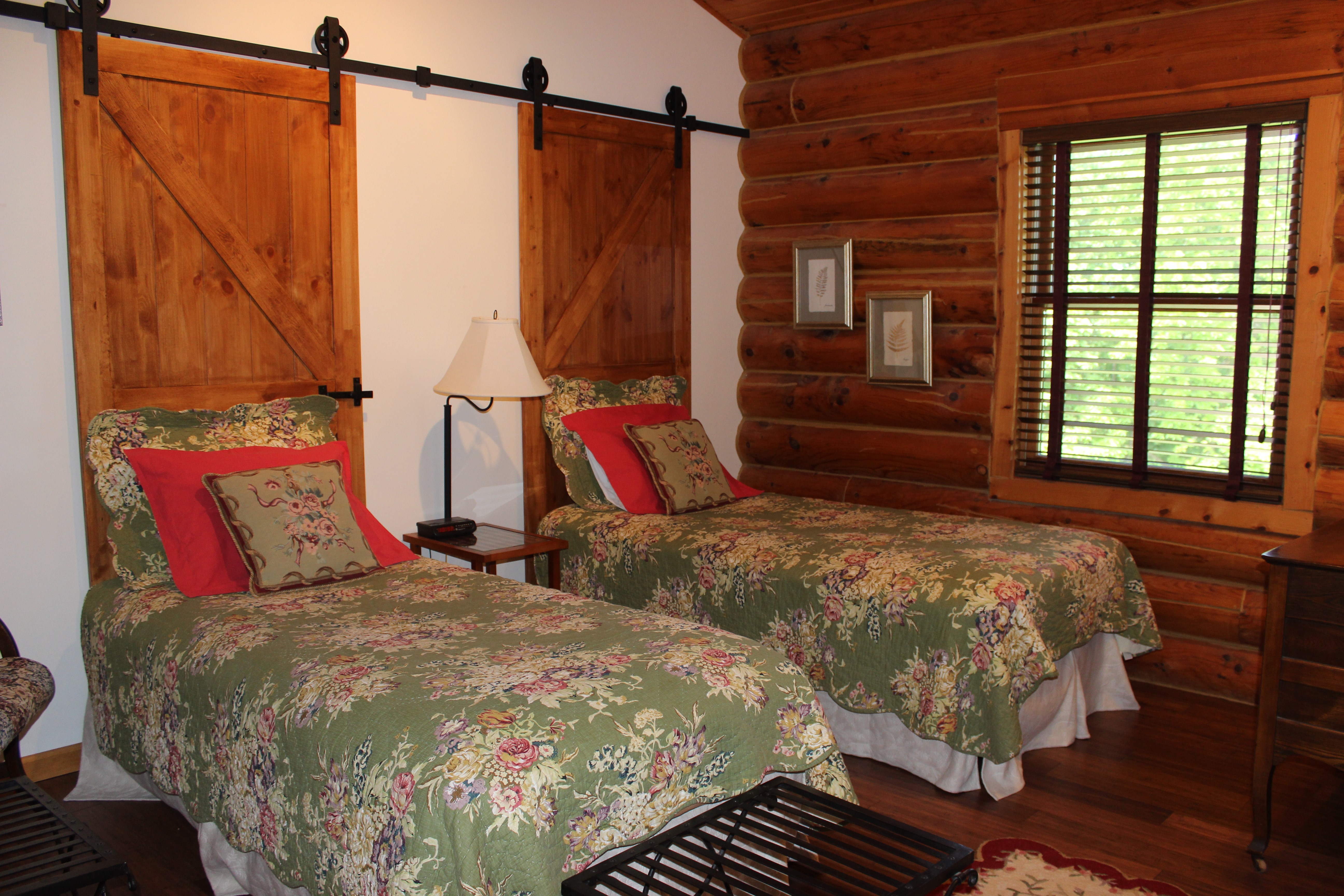 Twin beds covered with mossy green floral quilts, set against barnwood headboards.