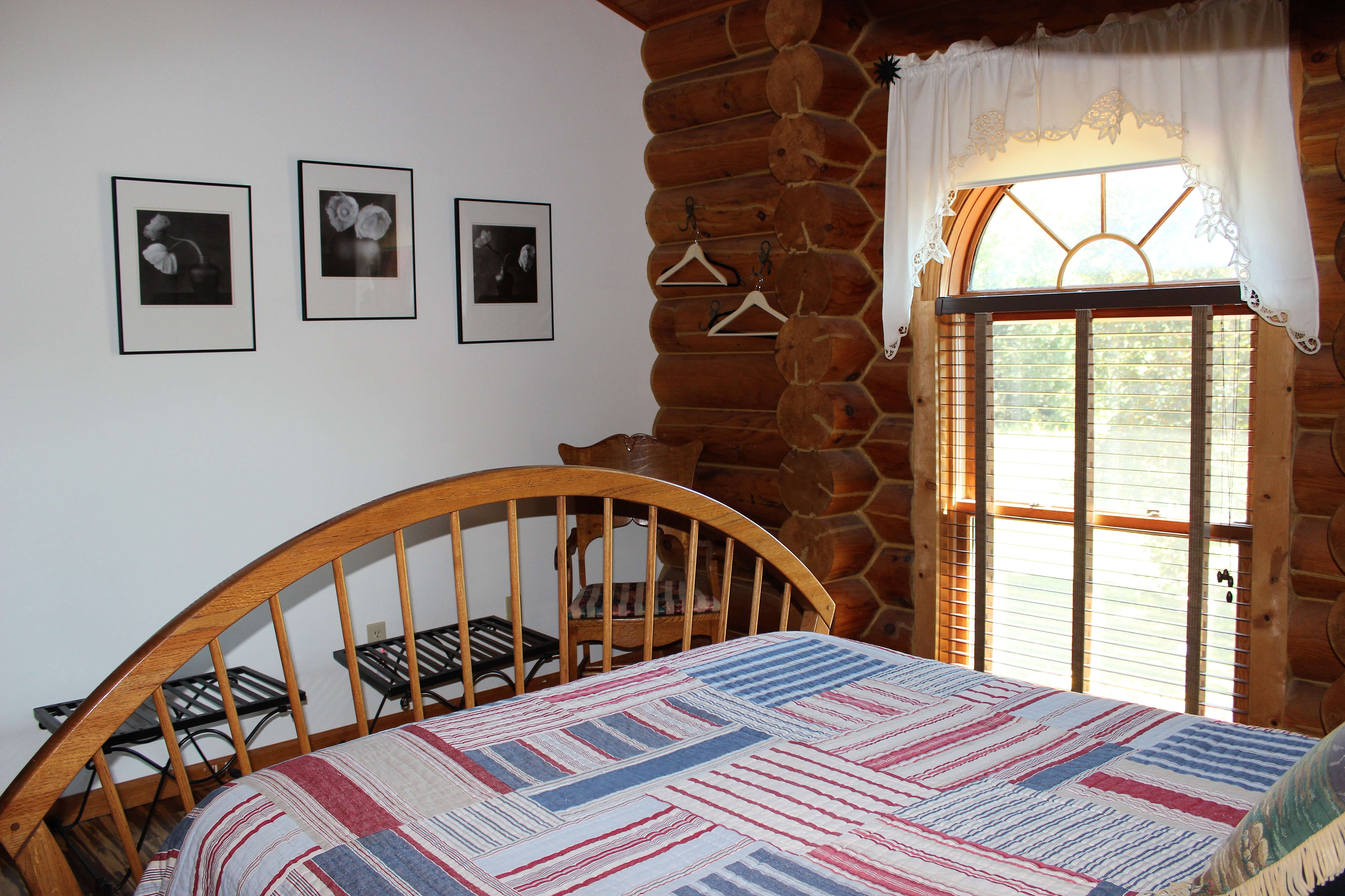 Queen sized wooden spindle bed covered with red, white and blue patchwork quilt