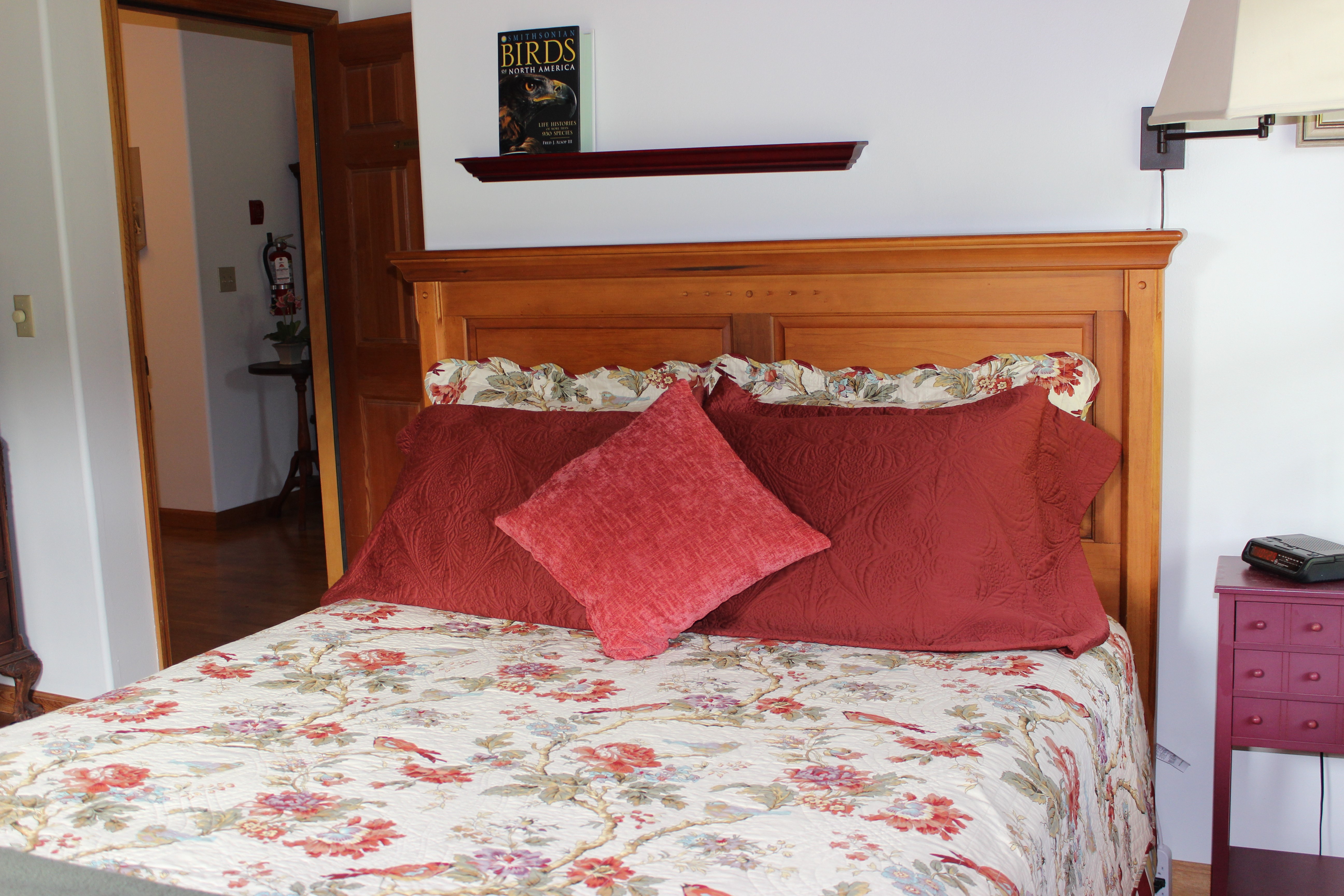 Queen sized bed with bird themed bedding and throw pillows