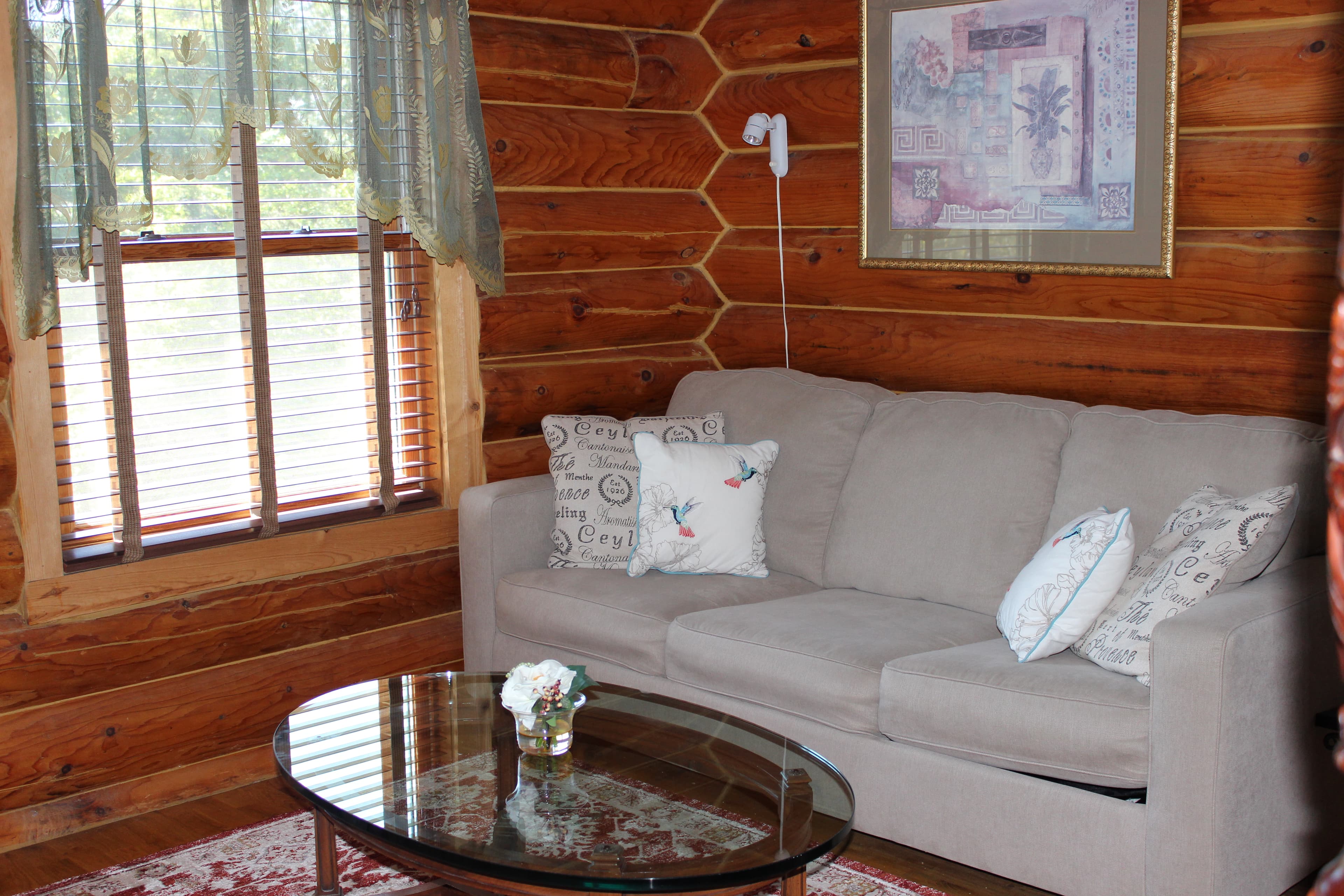Sitting area with comfortable tan sofa sleeper and glass cocktail table.