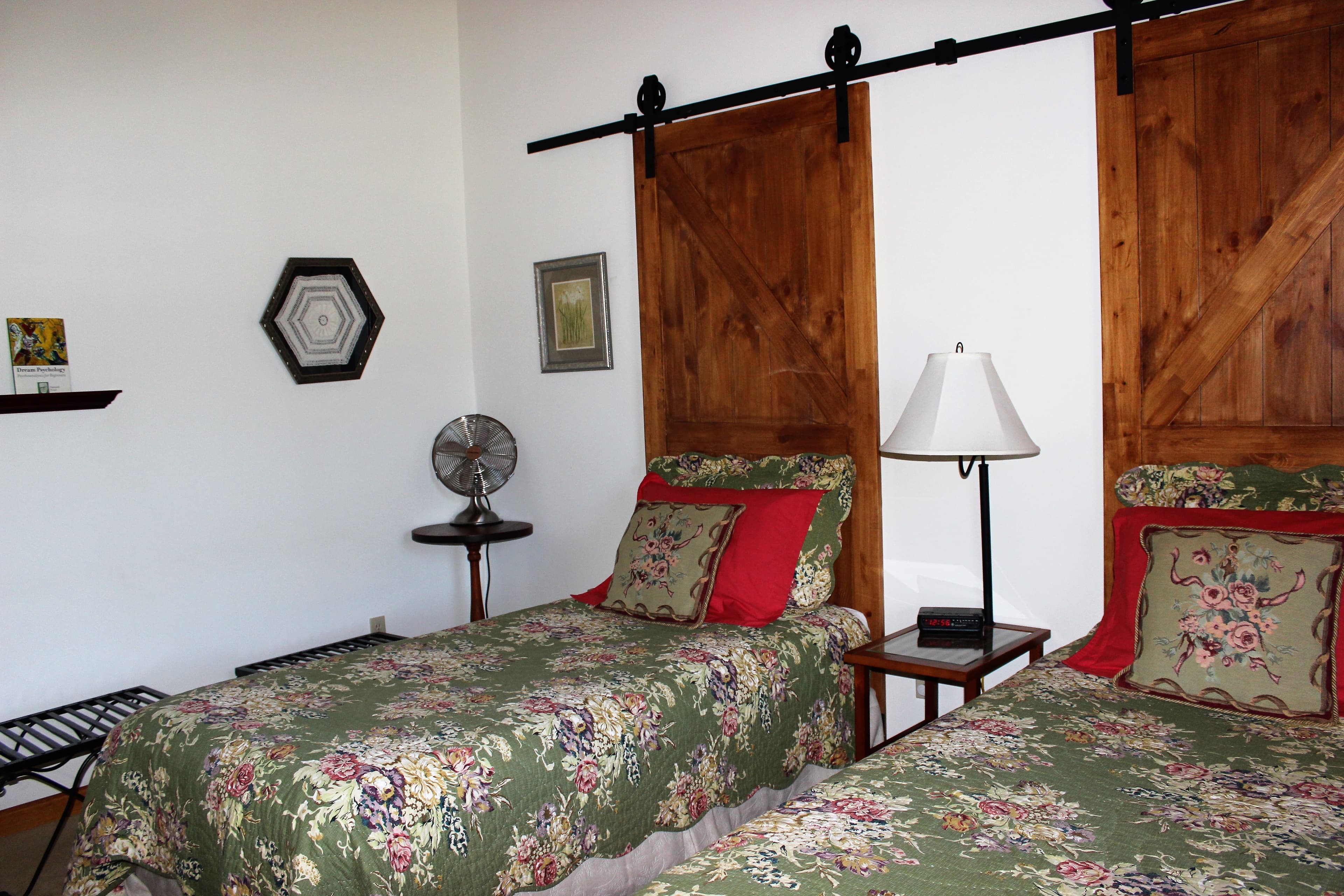 Twin beds covered with mossy green floral quilts, set against barnwood headboards.