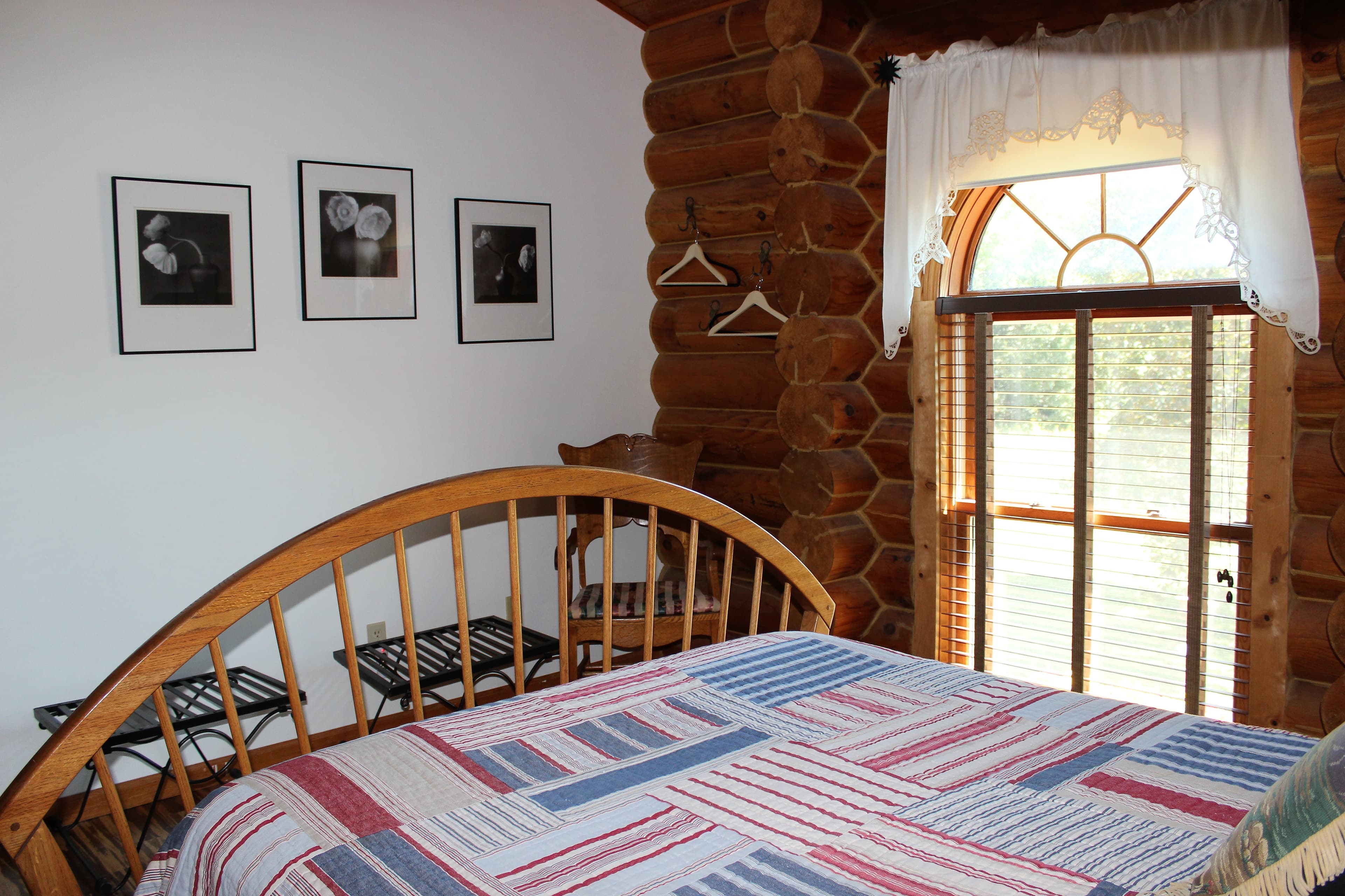 Queen sized wooden spindle bed covered with red, white and blue patchwork quilt