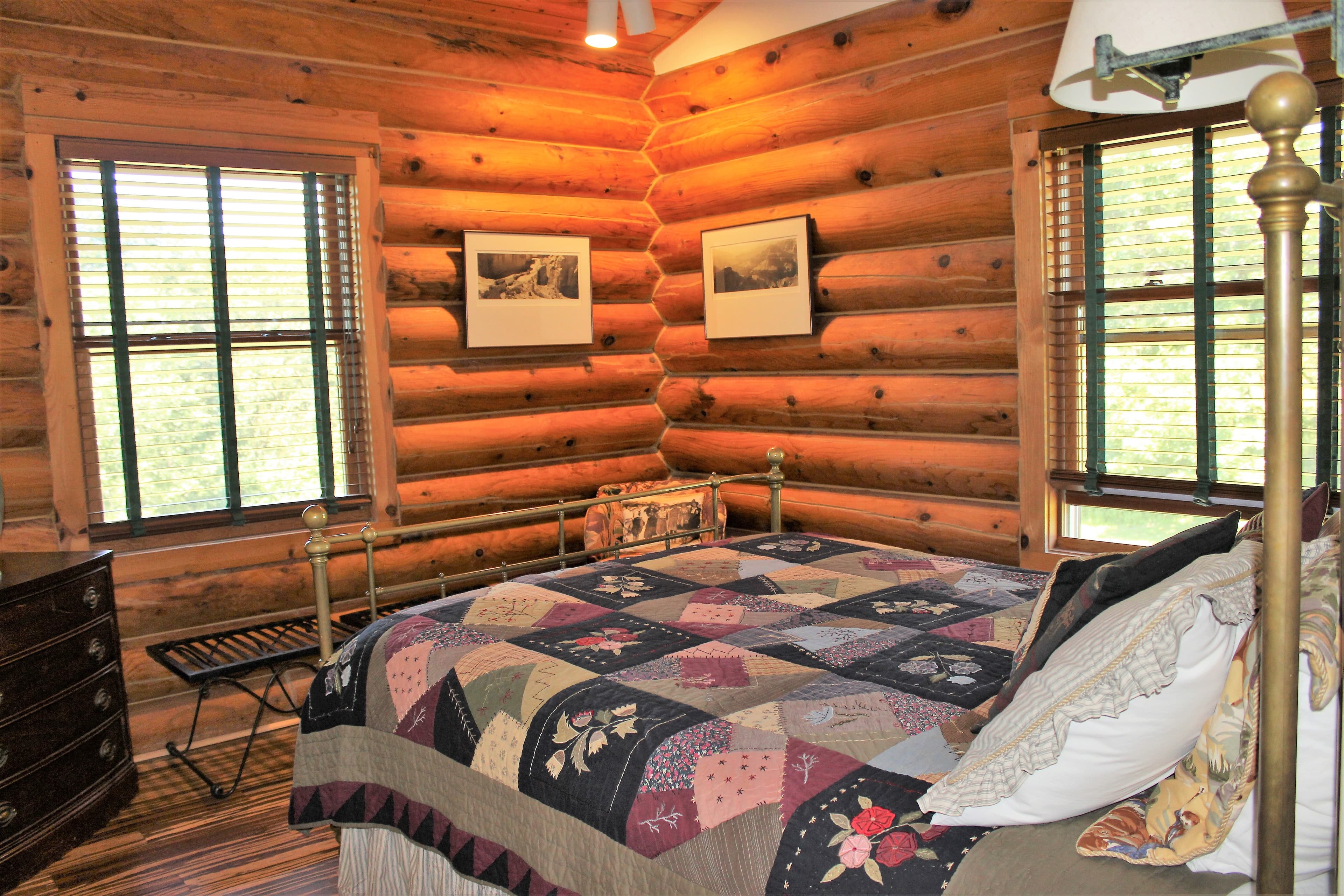 Antique brass with beautiful multi colored quilt, corner room with log walls.