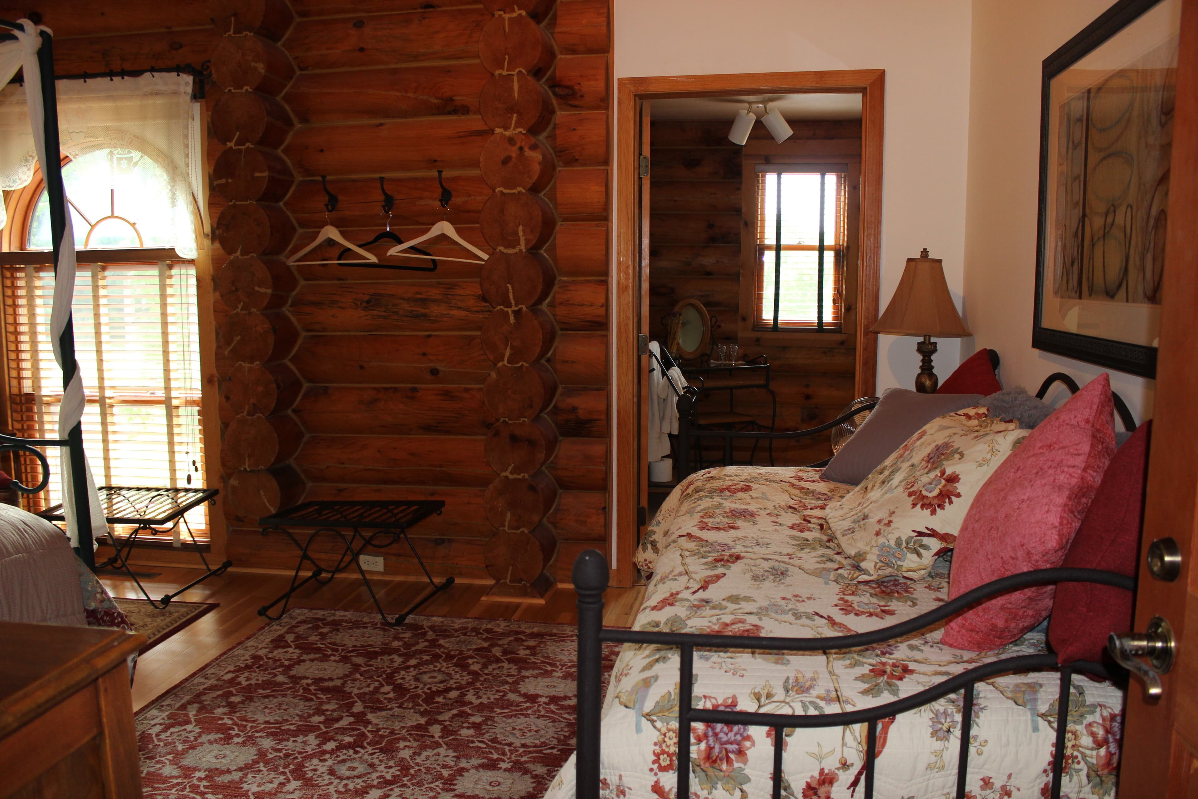 Wrought iron daybed with bird themed bedding and pillows. Hardwood floor with burgundy area rug.