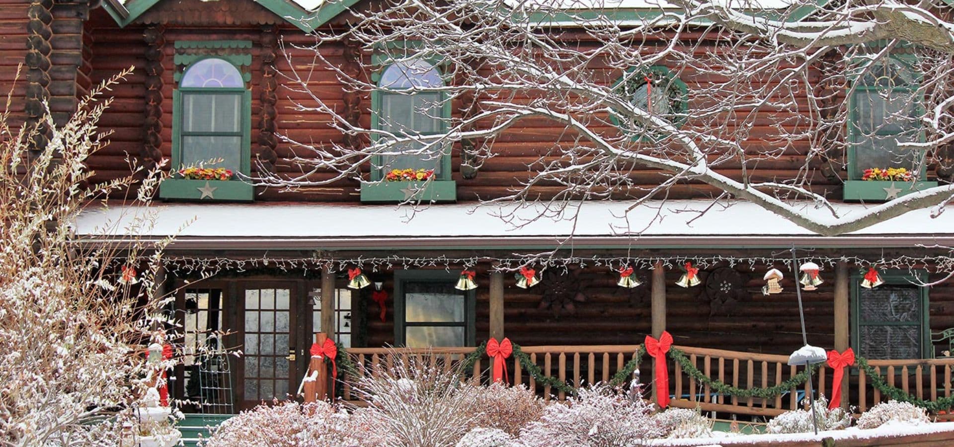 A snow-covered log cabin adorned with holiday decorations.