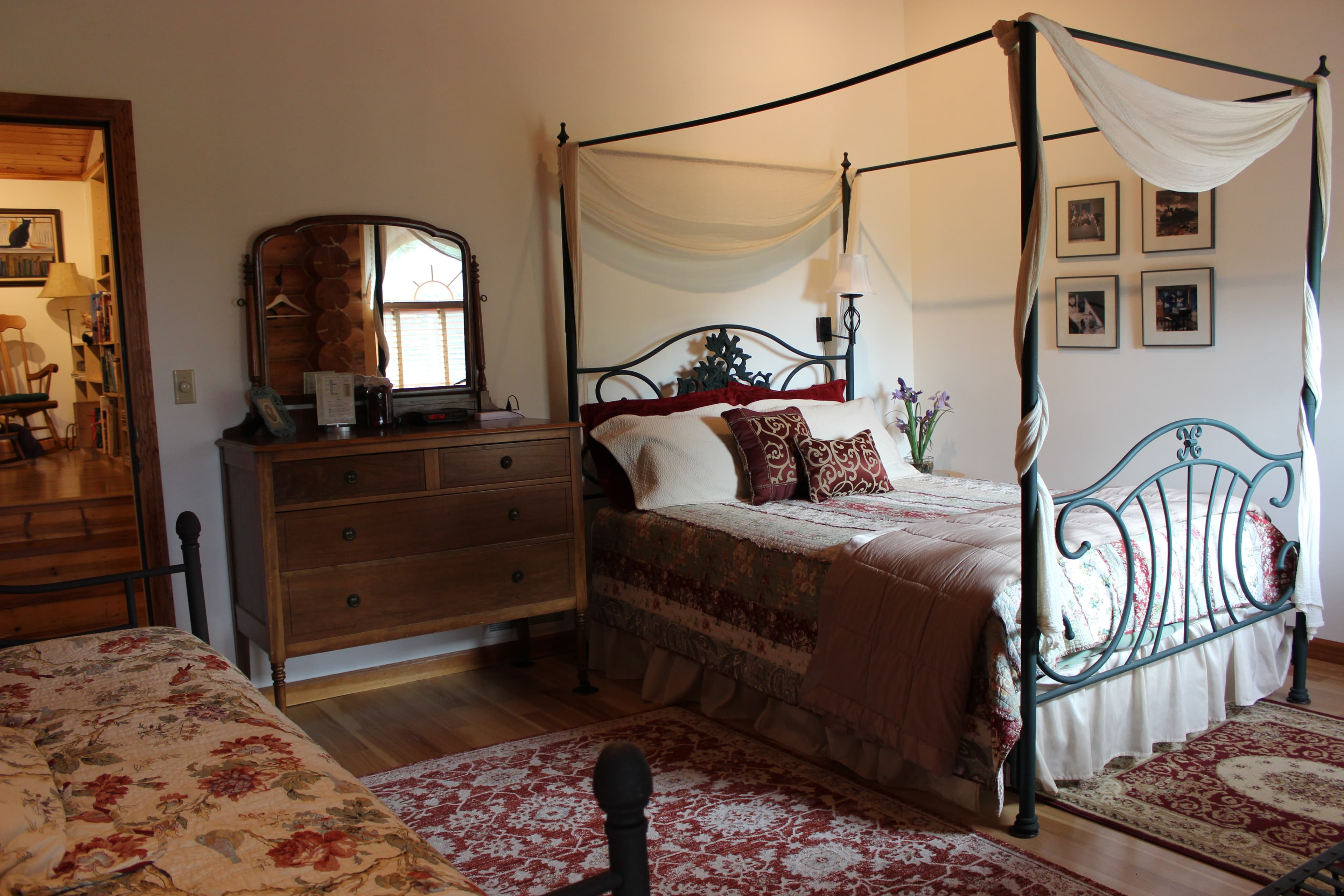 Queen sized wrought iron canopy bed with dresser and mirror.
