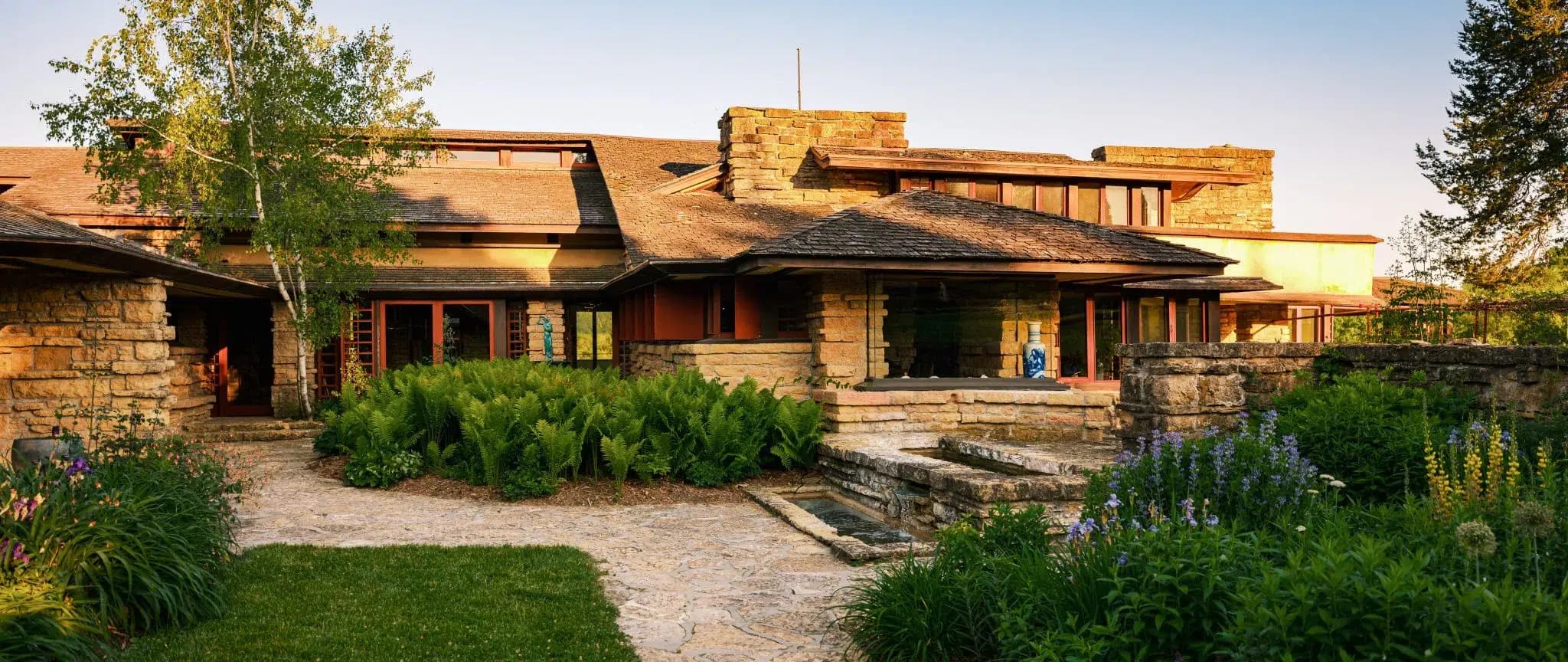 A modernist stone house surrounded by lush greenery and landscaped gardens. A modernist stone house surrounded by lush greenery and landscaped gardens.