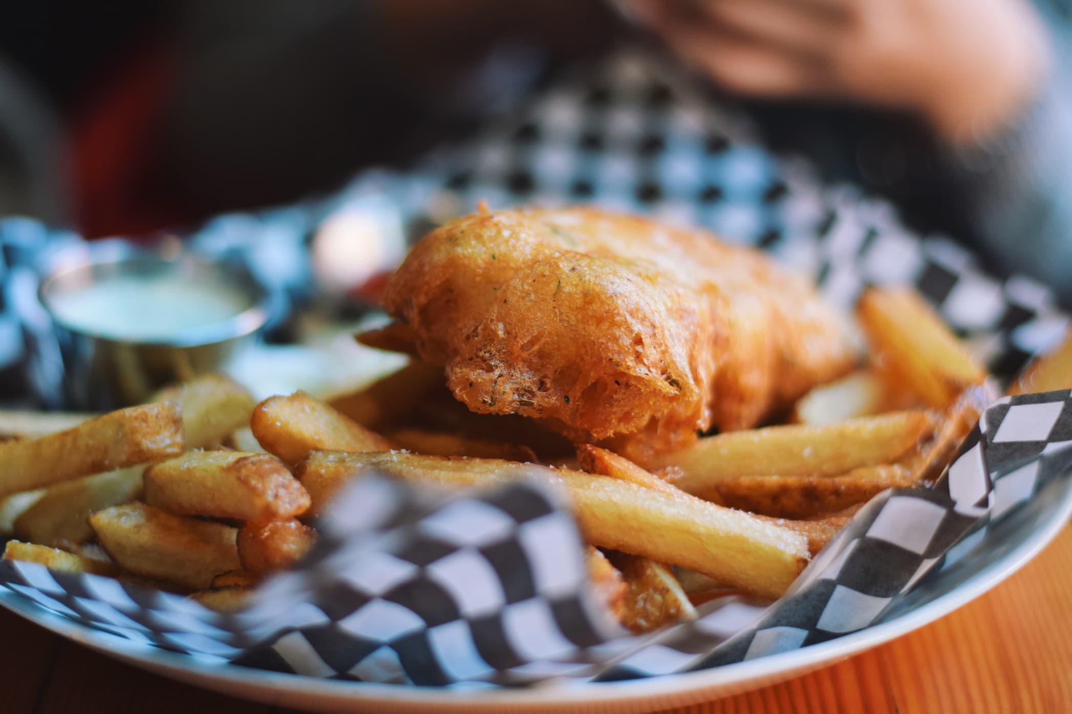 A plate of crispy fried fish served with golden French fries and a side of dipping sauce. A plate of crispy fried fish served with golden French fries and a side of dipping sauce.