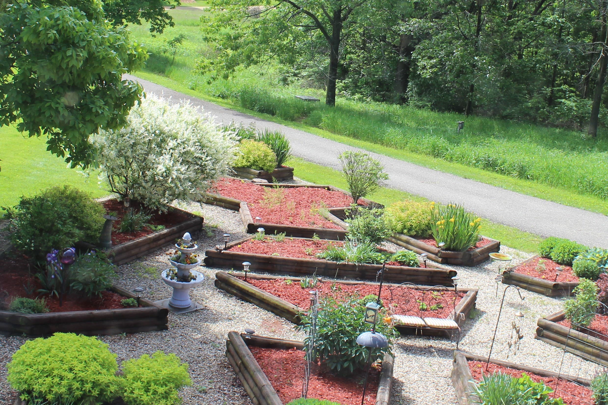 View from the octagonal window in bathroom. Colorful raised bed gardens and bird feeders.