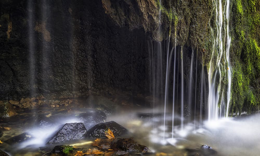A serene waterfall cascades over moss-covered rocks into a misty pool. A serene waterfall cascades over moss-covered rocks into a misty pool.